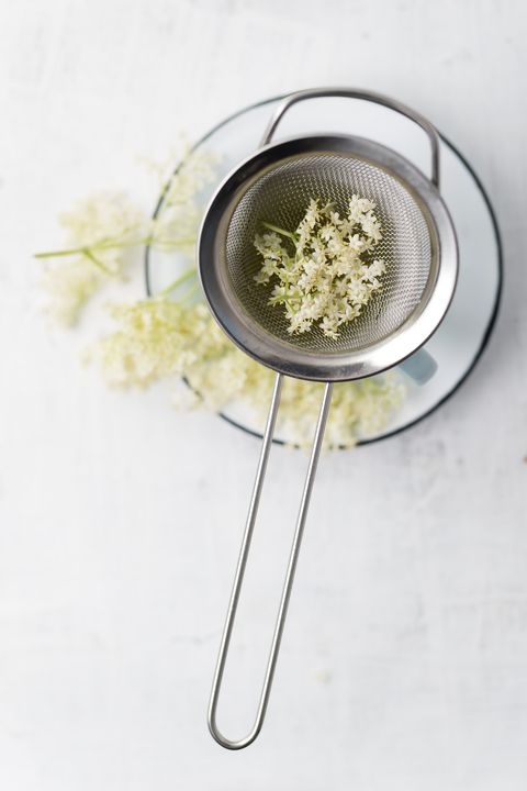 Strainer with elderflowers on a cup