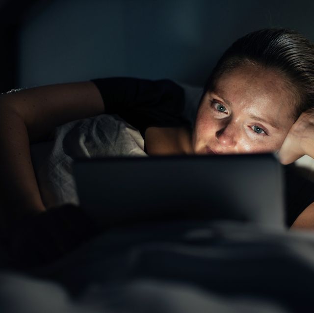 Woman using home tablet pc in bed.