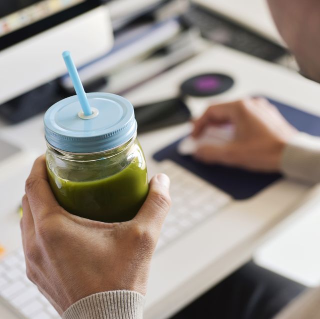man drinking a green smoothie at the office superfood powder men's health
