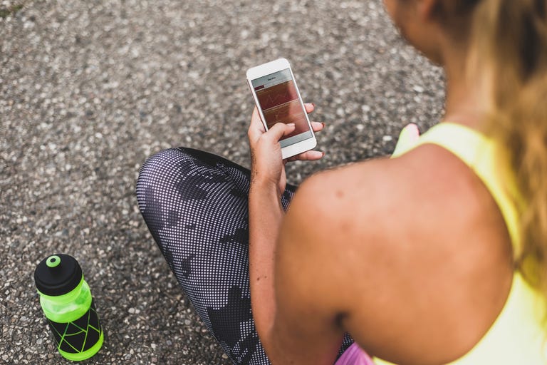 Sportive young woman looking at graph on cell phone display