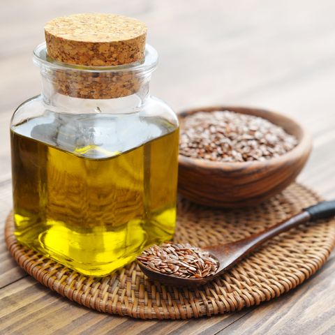 flax seeds and oil in bottle on wooden background