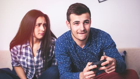 man playing video games while his girlfriend is getting mad at him