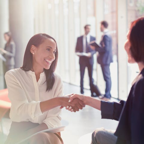 Smiling businesswomen handshaking in office lobby