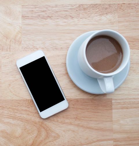 High Angle View Of Fresh Latte Served By Mobile Phone On Table