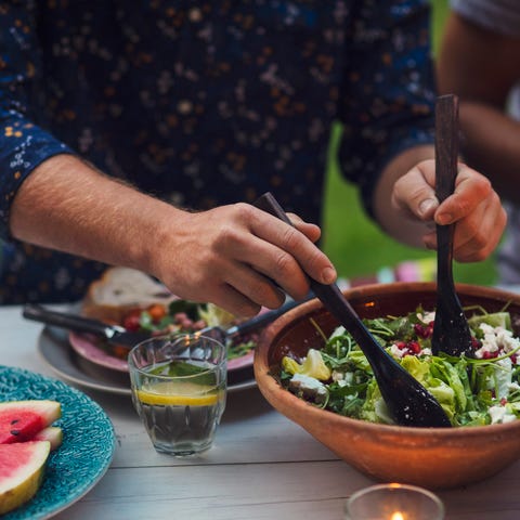 midsection of man mixing salad at table during garden party mens health weight loss tips