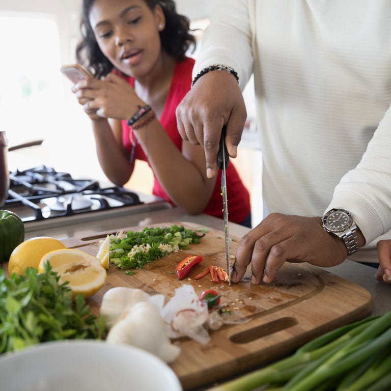 African American father and daughter cooking in kitchen