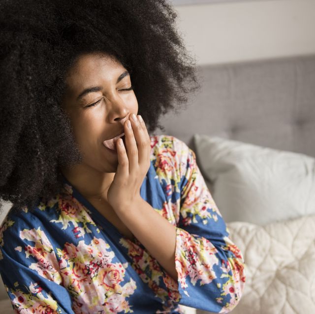 African American woman sitting in bed and yawning