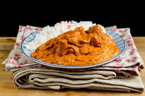 Chicken Curry With Rice Served In Plate On Napkin And Table Against Black Background