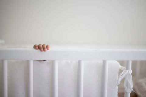 cropped image of baby hand in crib at home