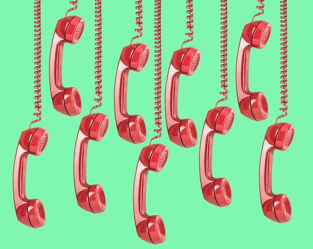 9 vintage red landline telephone receivers hanging down on green background