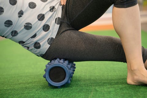 woman using a foam roll on her leg to release tension and help with muscle pain in the exercise class