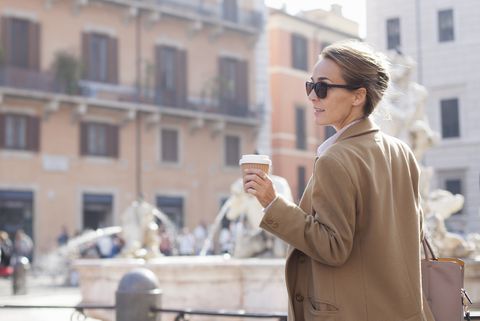 Elegant woman walking with takeaway coffee in sustainable coffee cup, Piazza Navona, Rome