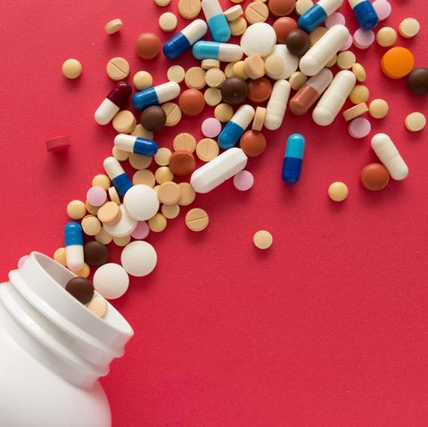 Group of assorted colorful tablets. Capsules spilling out of white bottle.