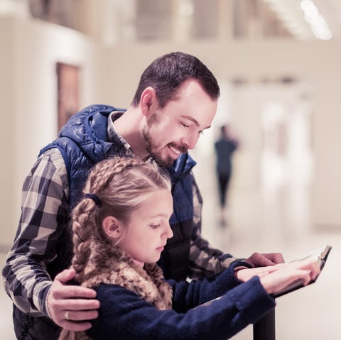 Father and daughter reading guide smiling father and daughter reading guide during visit to museum