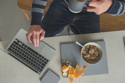 man eating breakfast whilst on laptop