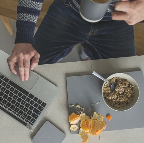 man eating breakfast whilst on laptop