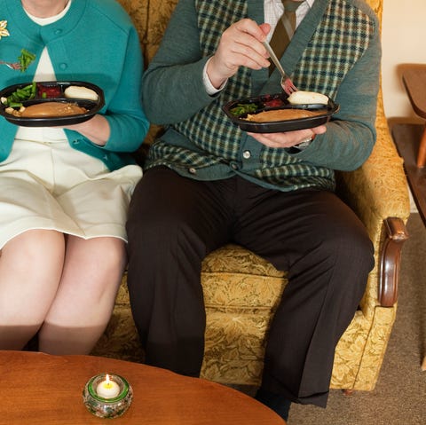 man and woman on couch holding tv dinners man and woman on couch holding tv dinners