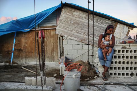 san isidro, puerto rico   december 23  mother isamar holds her baby saniel, 9 months, at their makeshift home, under reconstruction, after being mostly destroyed by hurricane maria, on december 23, 2017 in san isidro, puerto rico their neighborhood remains without electricity barely three months after hurricane maria made landfall, approximately one third of the devastated island is still without electricity while the official death toll from the massive storm remains at 64, the new york times recently reported the actual toll for the storm and its aftermath likely stands at more than 1,000 a recount was ordered by the governor as the holiday season approached  photo by mario tamagetty images