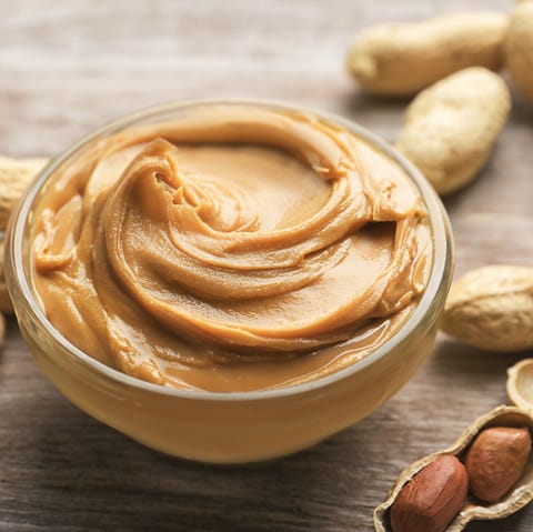 Glass bowl with peanut butter on wooden background