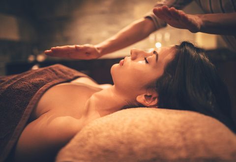 Woman lying down and relaxing with wellness massage from professional therapist in wellness spa salon