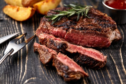 Juicy steak medium rare beef with spices on wooden board on table