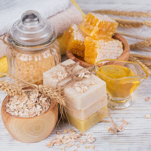 honeycomb, sea salt, oats and handmade soap with honey on white rustic wooden background natural ingredients for homemade facial and body mask or scrub healthy skin care spa concept