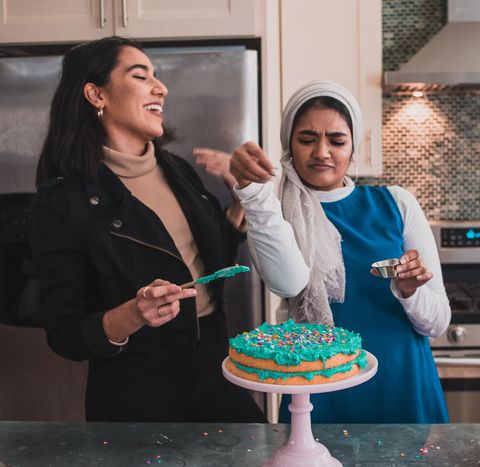 تبریک تولد خواهر دو نسل جوان زن مسلمان با حجاب و بی حجاب با آب پاشی و تزئین کیک تولد دوستانشان عکس نوشته rwaida izar برای muslimgirlcom
