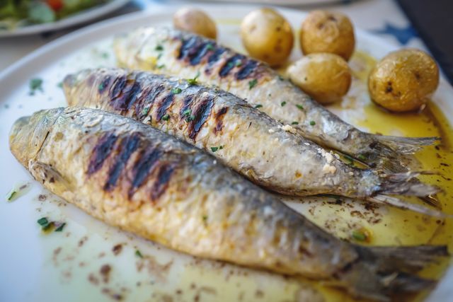 close up of grilled sardine fishes served in oil with baked potatoes, a traditional portuguese food, portugal