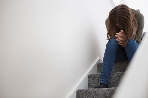 Teenage girl sitting on stairs with head down in despair amazon