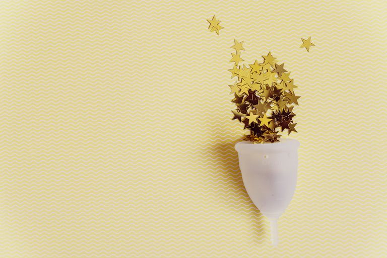 Menstrual cup with sparkling stars on yellow background