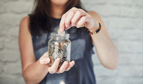 young woman putting money into a jar
