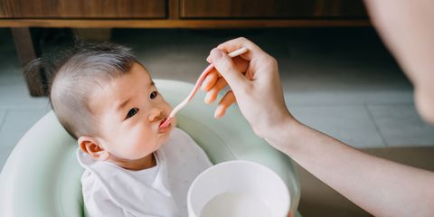 Mother feeding baby for the first time with solid food at home