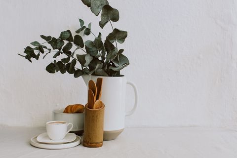 Coffee cup, croissant, Kitchen utensils and eucalyptus in a jug