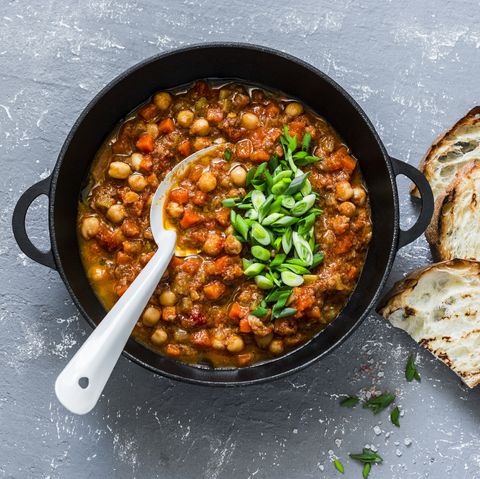 Vegetarian mushrooms chickpea stew in a iron pan and rustic grilled bread on a gray background, top view. Healthy vegetarian food concept. Vegetarian chili