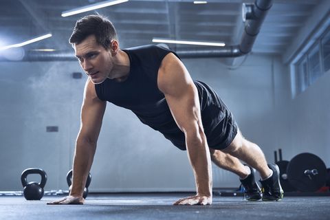Athletic man doing pushups exercise at gym