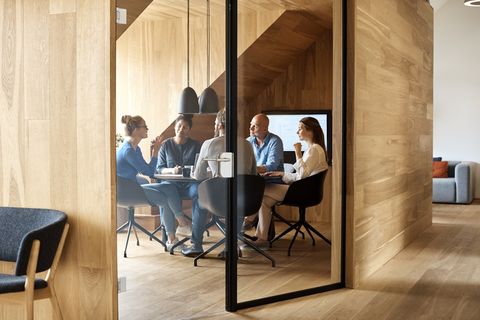 business professionals discussing in meeting seen through glass door at office