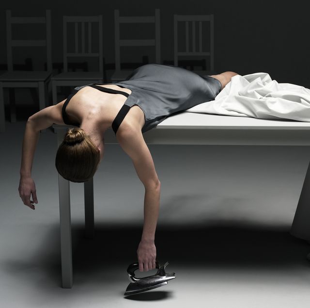 Woman lying on table with sheet holding iron
