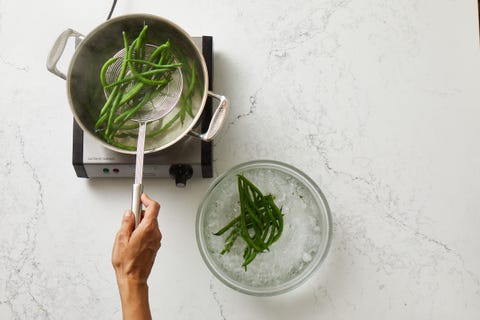 using slotted spoon to transfer blanched green beans to ice water