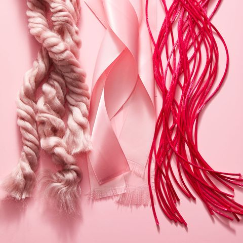 three strands of ribbon and rope with frayed ends in various shades of pink on a pink background