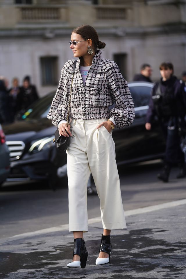 paris, france   march 03 a guest wears sunglasses, earrings, a black and white tweed jacket, white cropped flared pants, black and white shiny pointy shoes, a bag, outside chanel, during paris fashion week   womenswear fallwinter 20202021 on march 03, 2020 in paris, france photo by edward berthelotgetty images