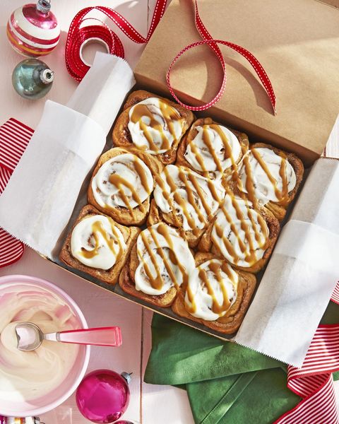 nine gingerbread rolls with frosting and glaze in a parchment lined gift box