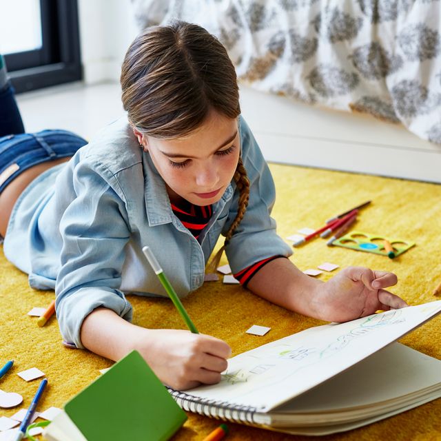 young girl on floor drawing with color pencils