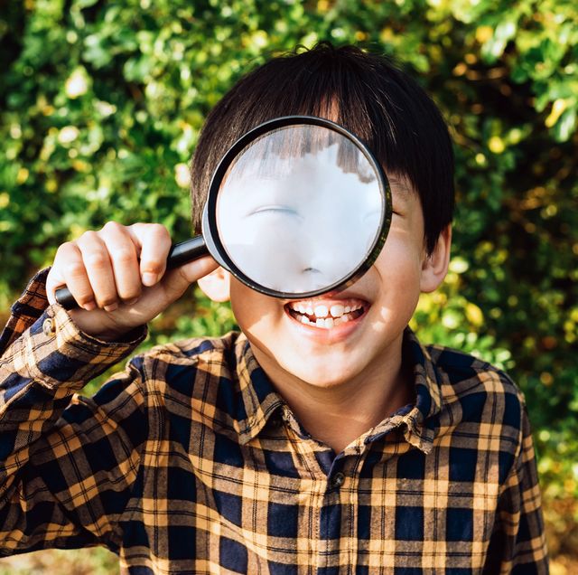 young boy holding microscope up to eye