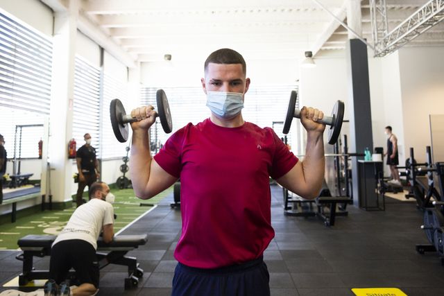 un joven levanta las pesas en un gimnasio de madrid con la mascarilla por la pandemia de la covid 19