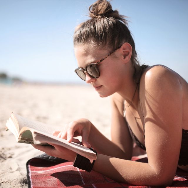 girl reading book on beach