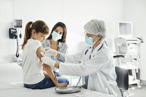 girl receiving covid 19 shot and looking at her arm