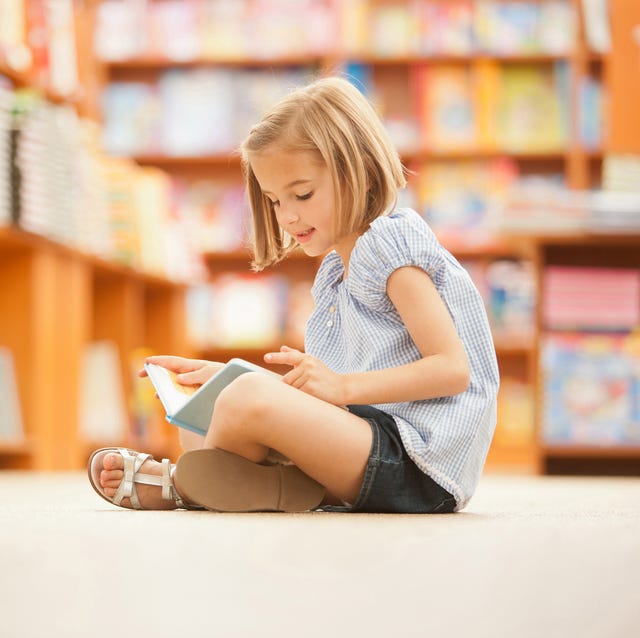 niña sentada leyendo niña en biblioteca leyendo