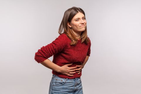 girl touching belly, grimacing from stomach ache, severe abdominal distress, symptoms of constipation