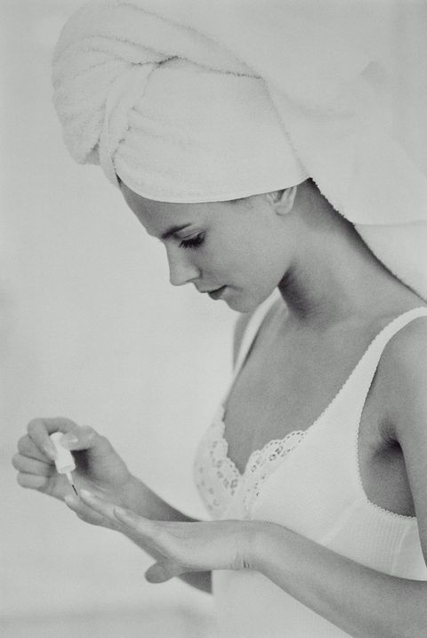 Girl with hair wrapped in towel, varnishing nails, B&W