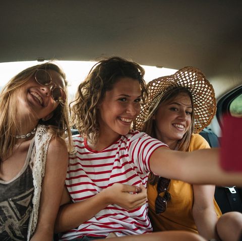 teenage girls doing selfie on back seat of the car